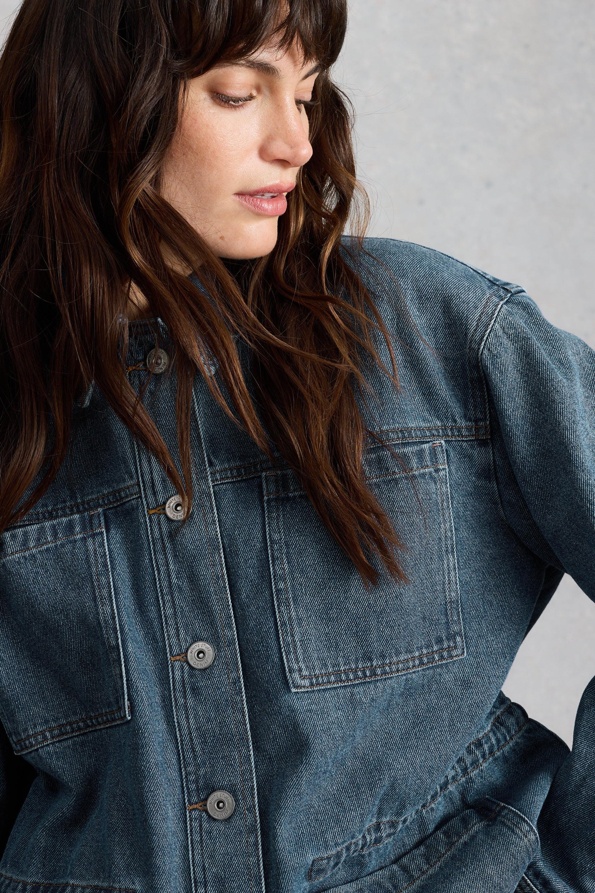 Woman wearing a blue denim jacket against a neutral background