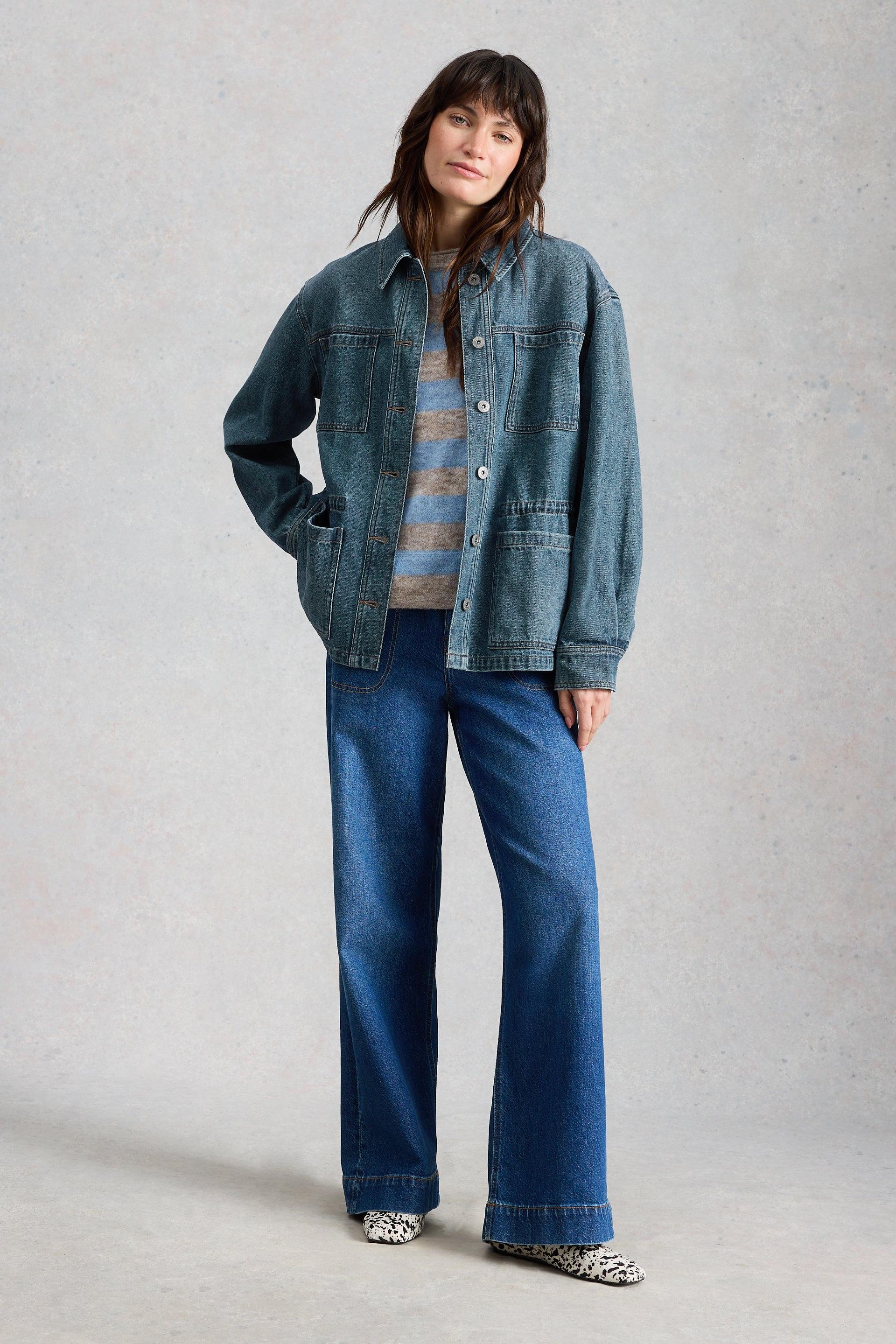 Person wearing an organic cotton denim jacket and jeans on a plain background