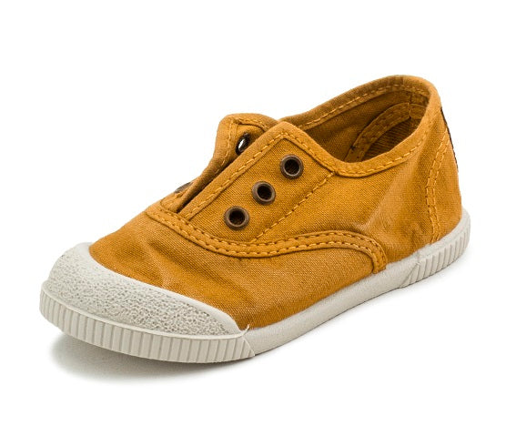 Yellow children's shoe with a white sole on a white background