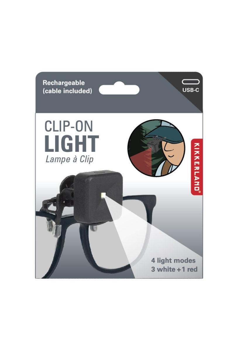 Kikkerland clip-on light packaging with a person using the light in the corner.