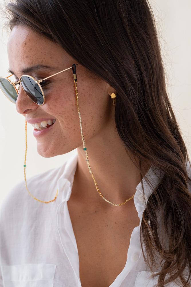 Woman wearing a gold chain eyeglass holder with a white shirt.