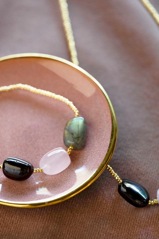 Bracelet with green and black beads on a pink dish