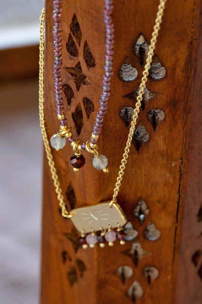Necklace with gold chain and colorful beads on a wooden stand