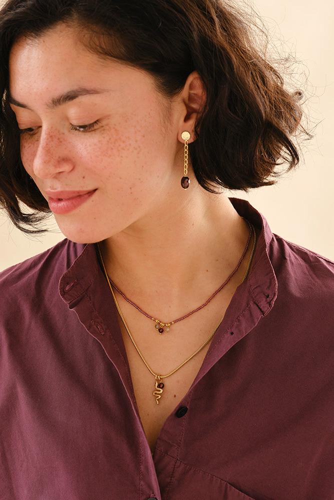 Woman wearing gold necklaces and earrings against a neutral background