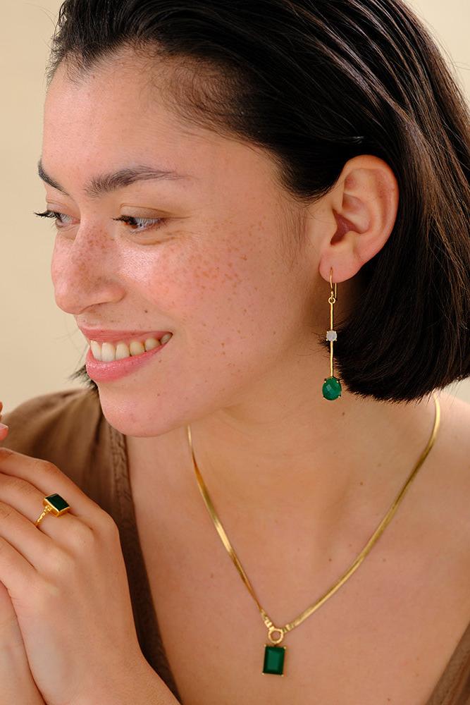 Woman wearing gold necklace and earrings with a neutral background
