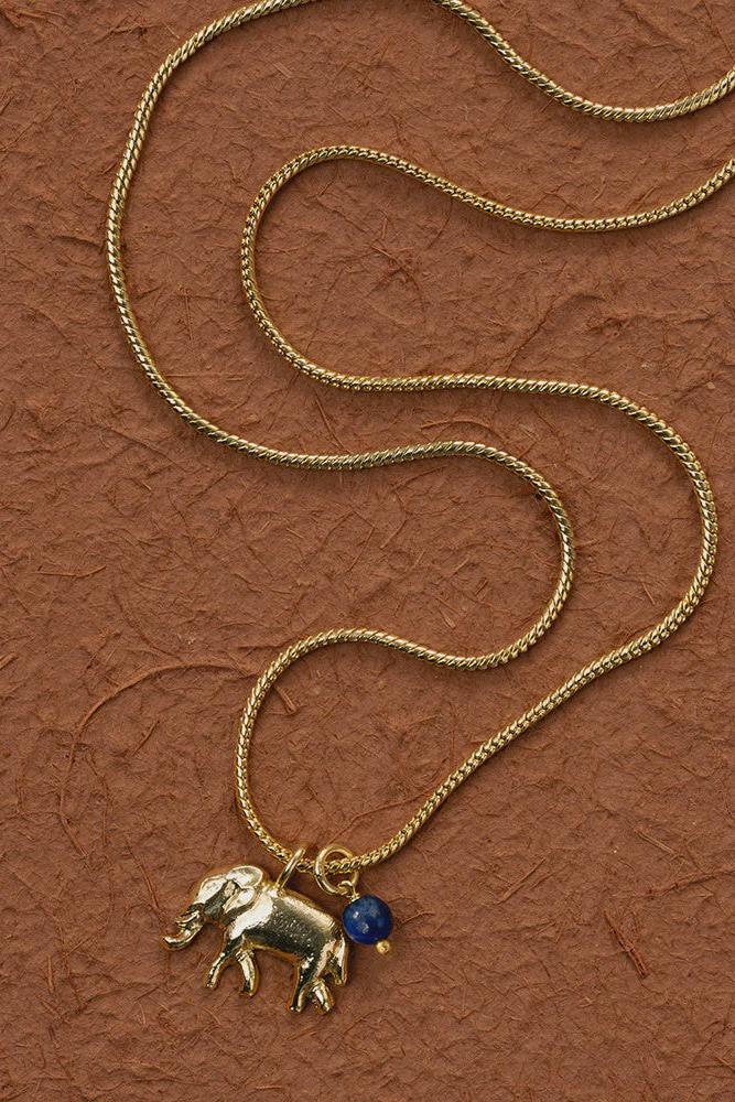 Gold necklace with an elephant pendant on a brown textured background