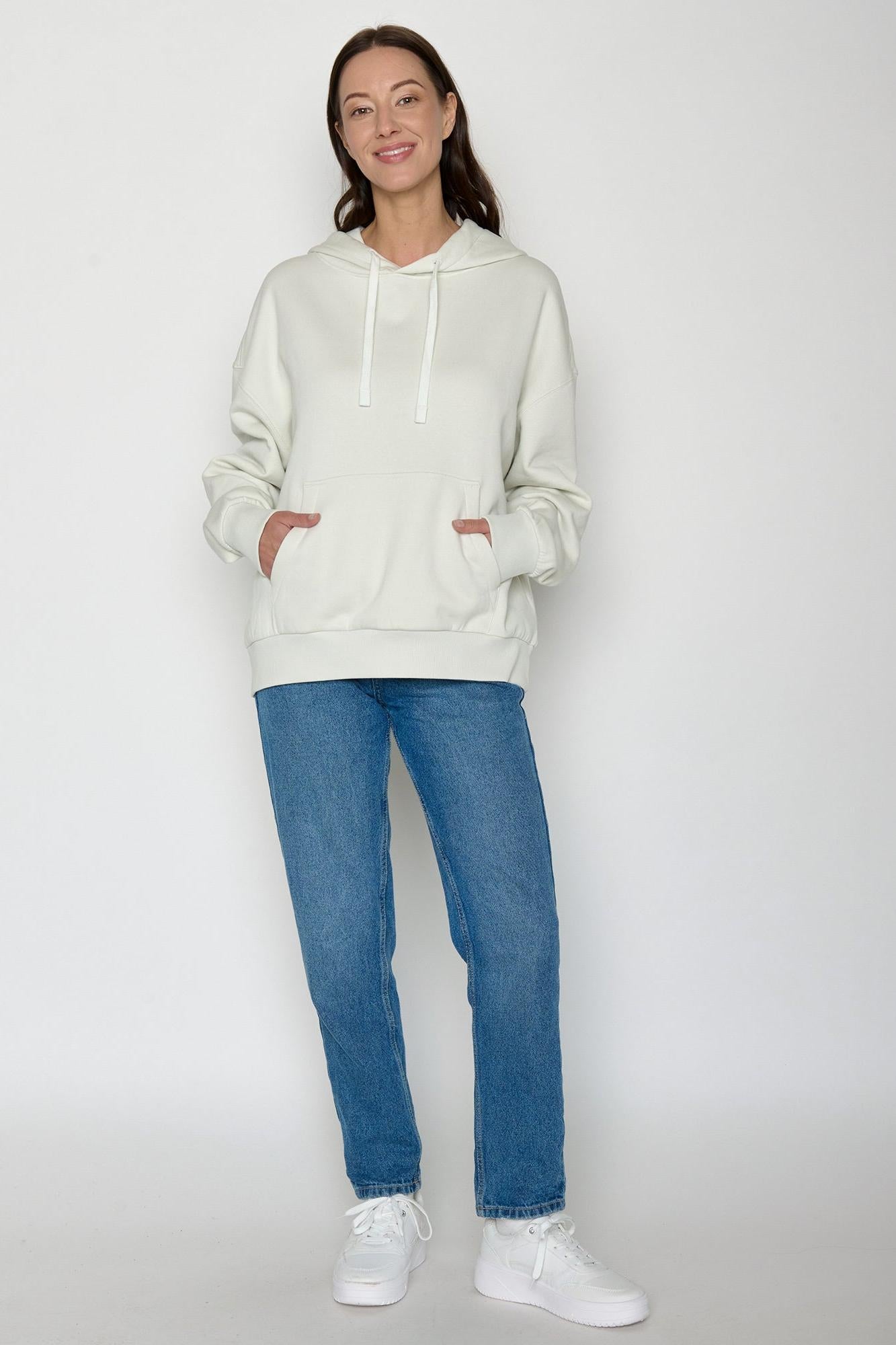 Person wearing a light-colored Greenbomb hoodie and blue jeans on a white background