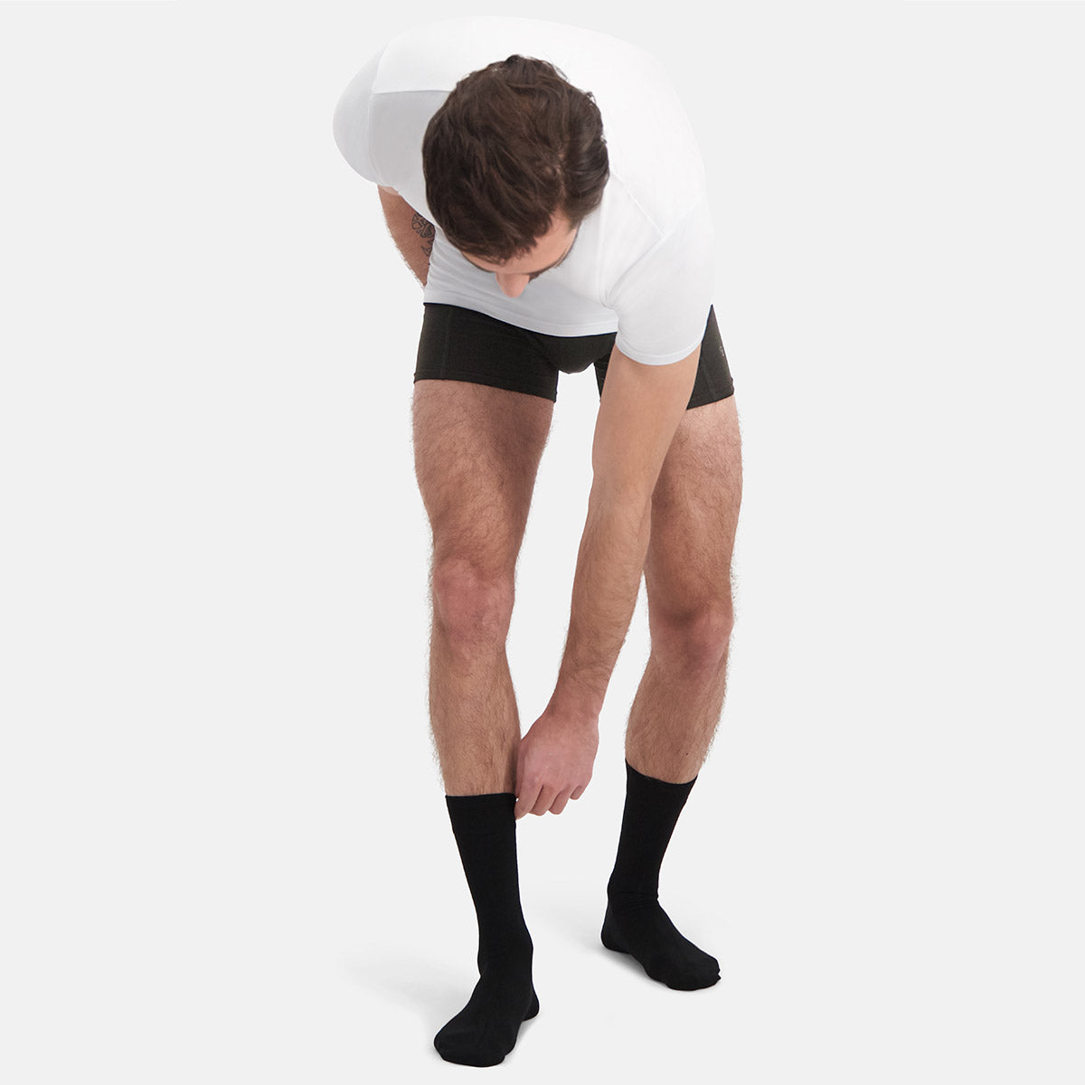 Person wearing black bamboo socks and underwear on a white background