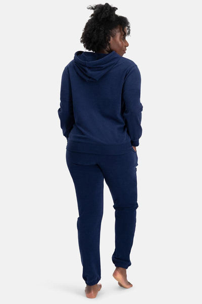 Person wearing a navy blue organic cotton hoodie and pants on a white background