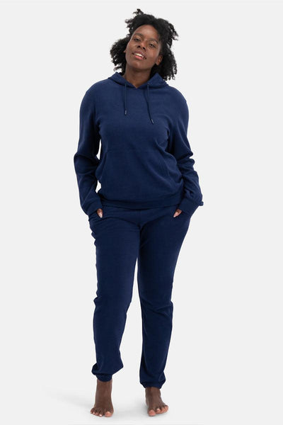 Person wearing a navy blue bamboo hoodie and pants on a white background