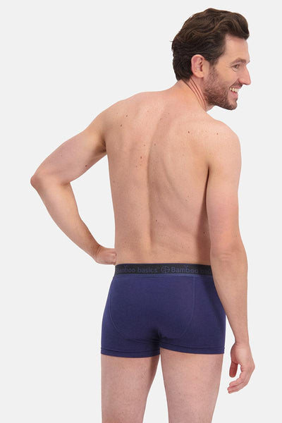 Man wearing navy blue boxer briefs on a white background
