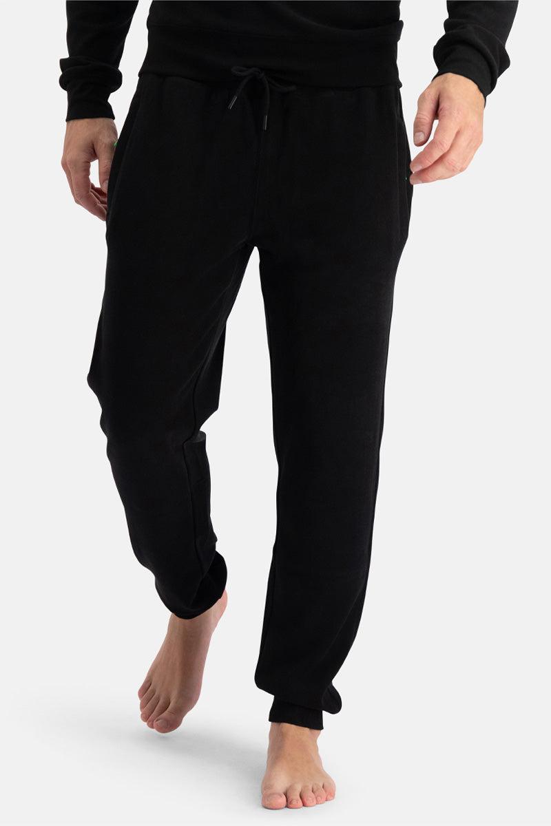 Person wearing black knitted sweatpants on a white background