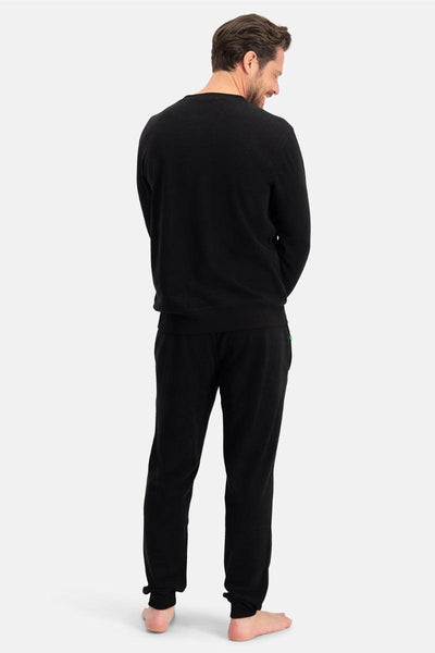 Man wearing a black long-sleeve shirt and pants on a white background