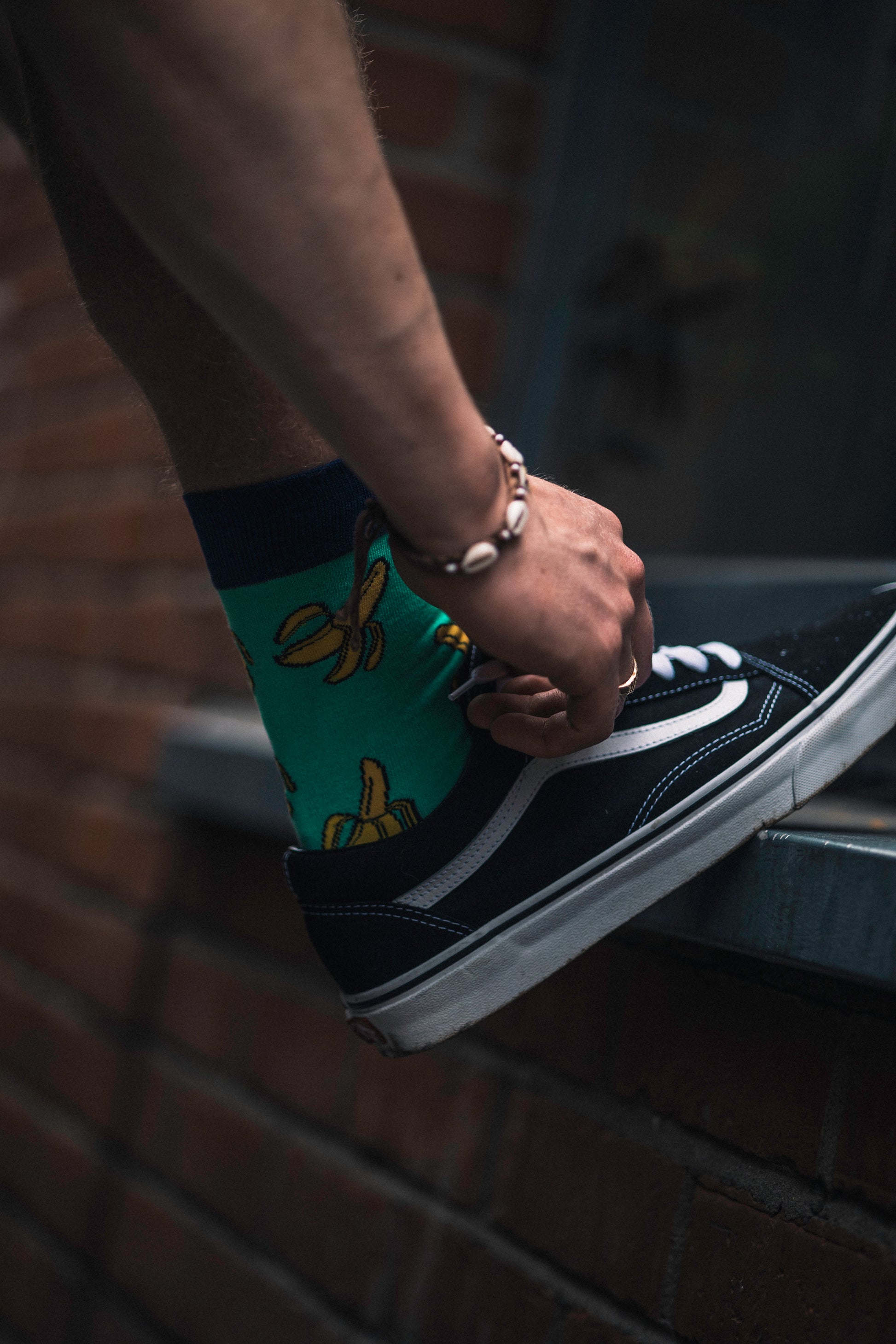 Person wearing a black and white sneaker with a colourful sole on a dark background
