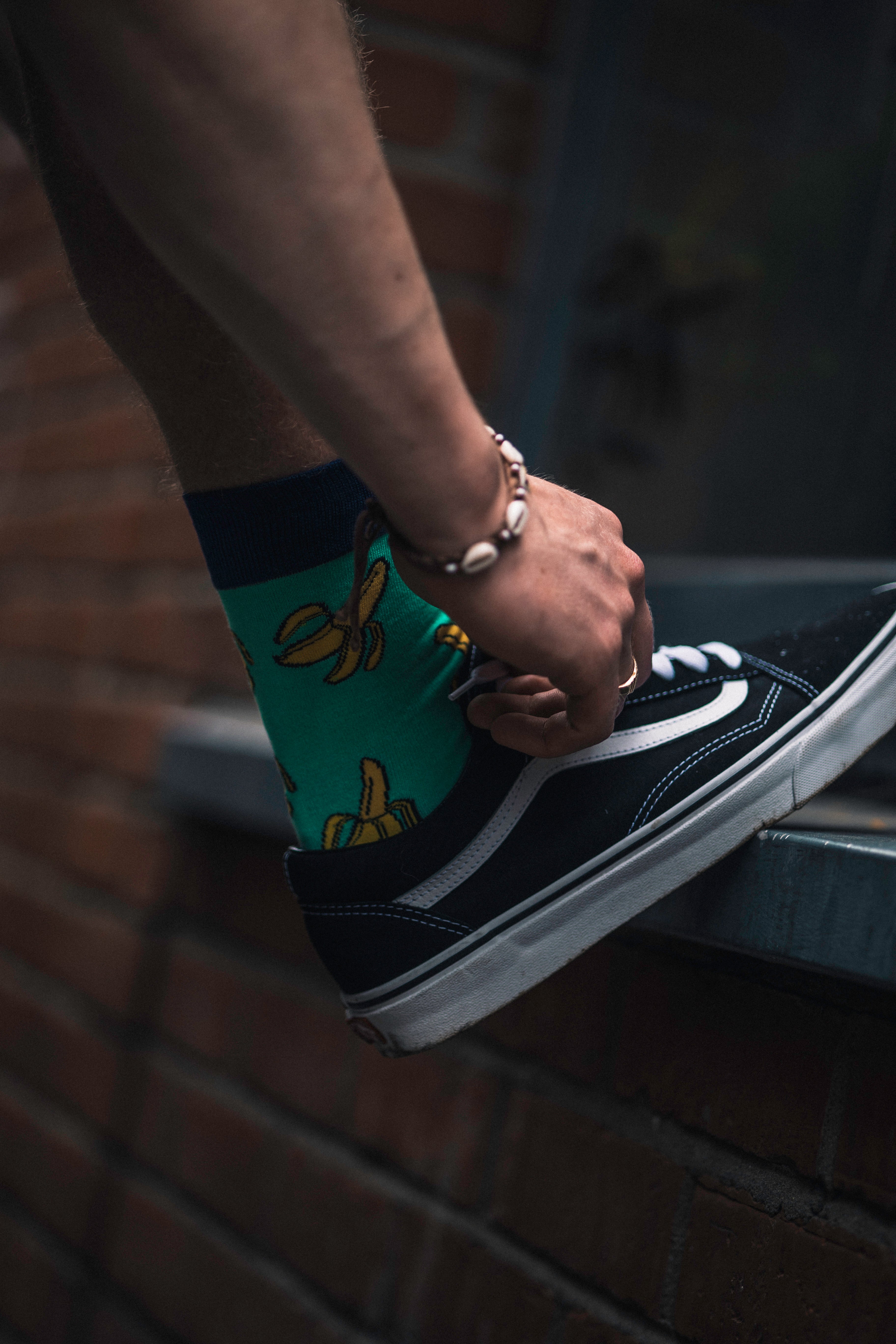 Person wearing a black and white sneaker with a colourful sole on a dark background