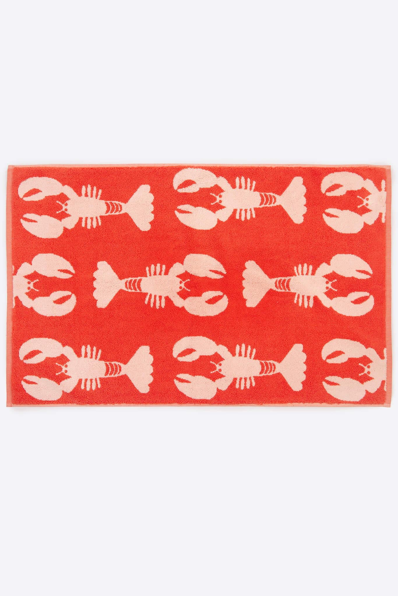 Red organic cotton towel with white lobster pattern on a white background