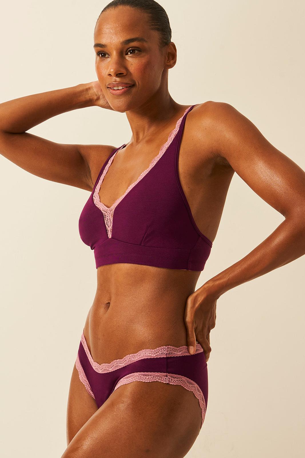 Woman wearing a sustainable underwear with pink accents against a beige background