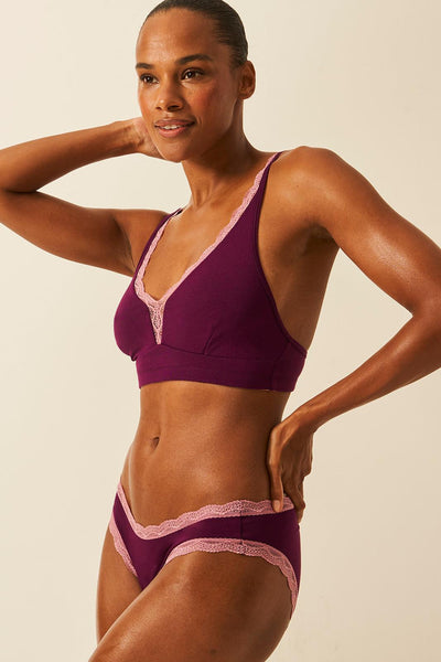 Woman wearing a sustainable underwear with pink accents against a beige background