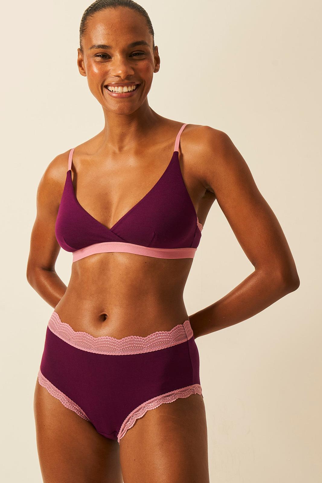 Woman wearing a purple bra with pink accents on a beige background