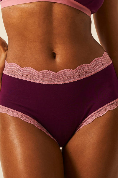 Purple lace-trimmed underwear on a person with a neutral background