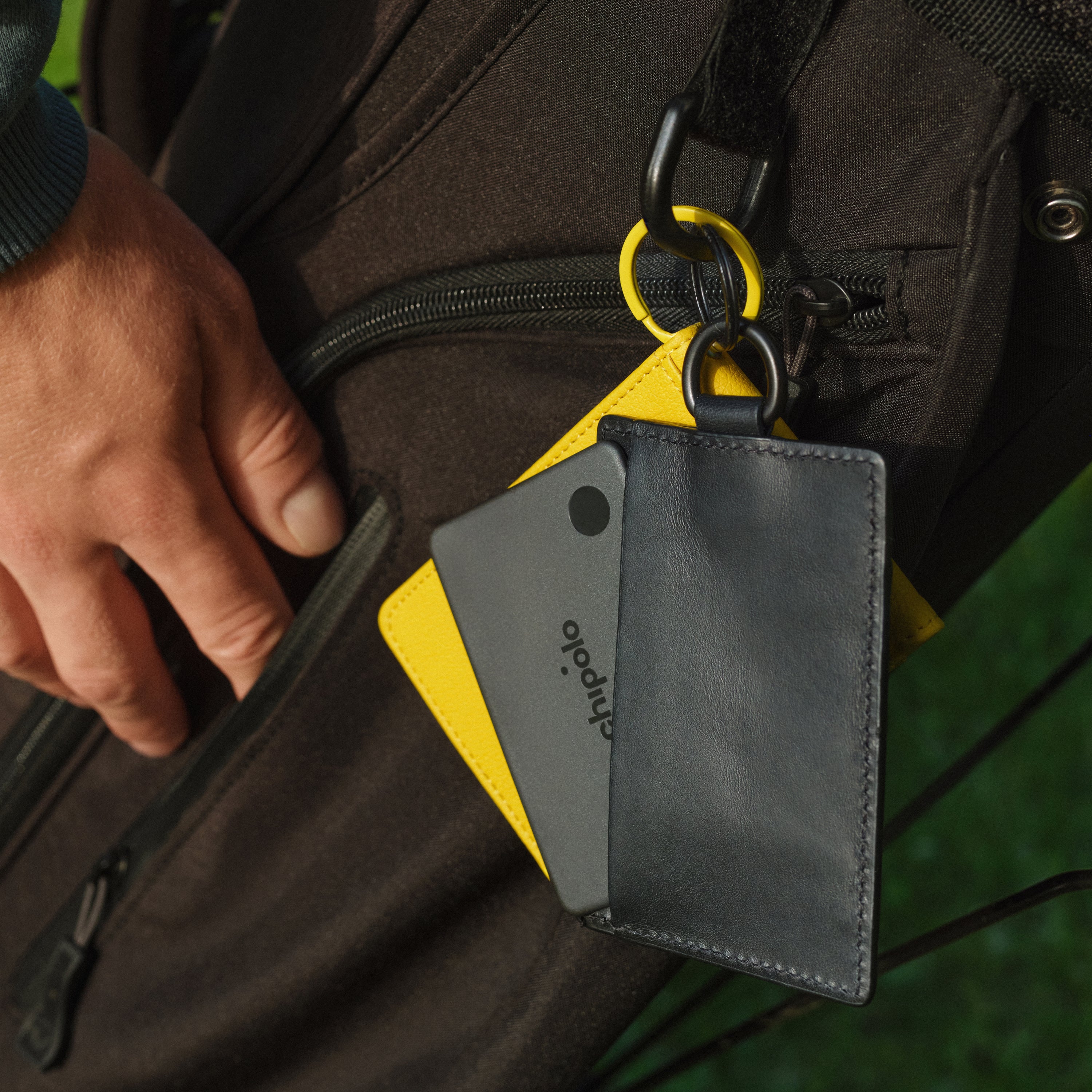 Black leather cardholder with 'chipolo' branding attached to a bag.