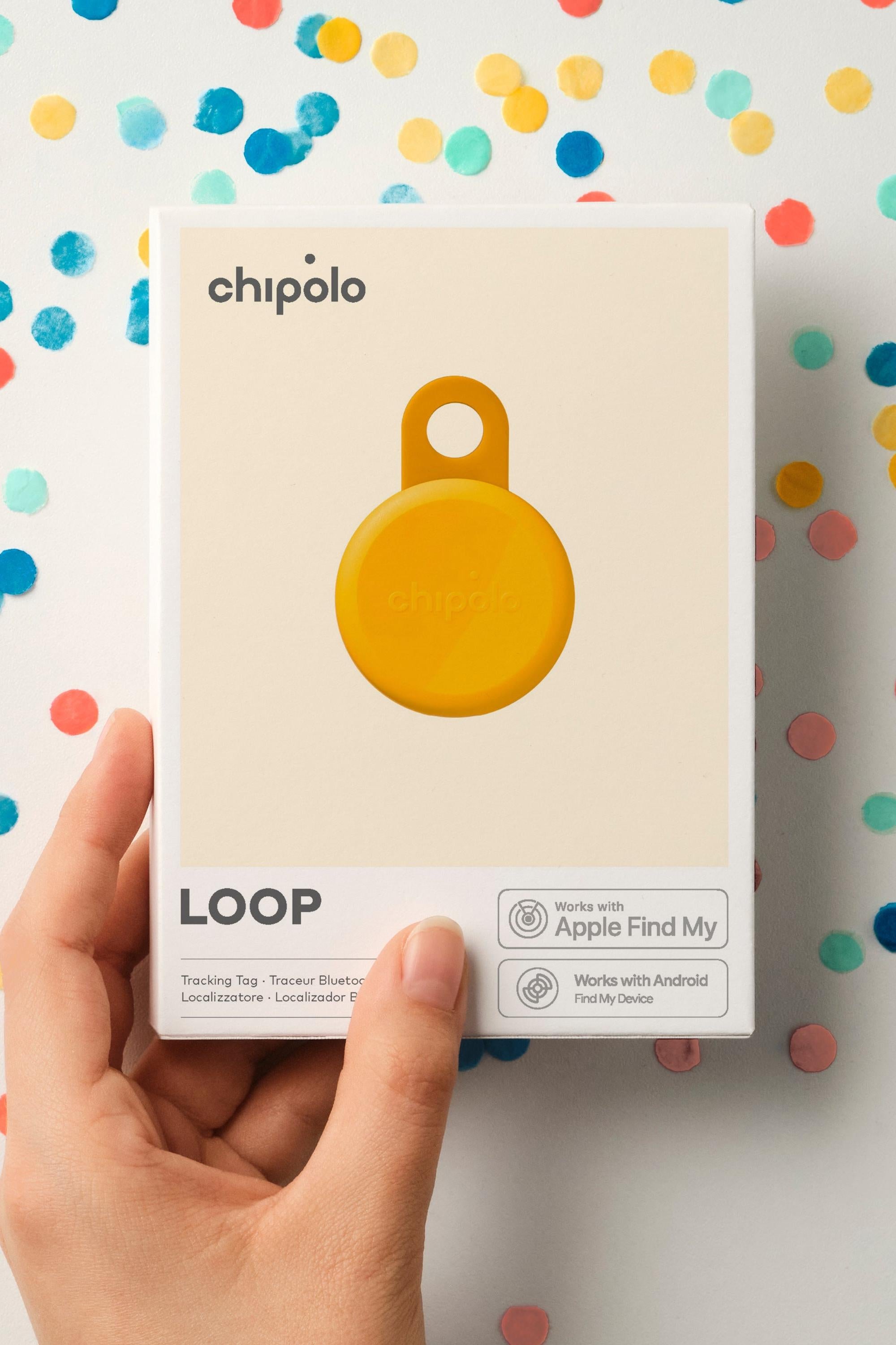 Hand holding a box of Chipolo Loop tracker against a colorful polka dot background