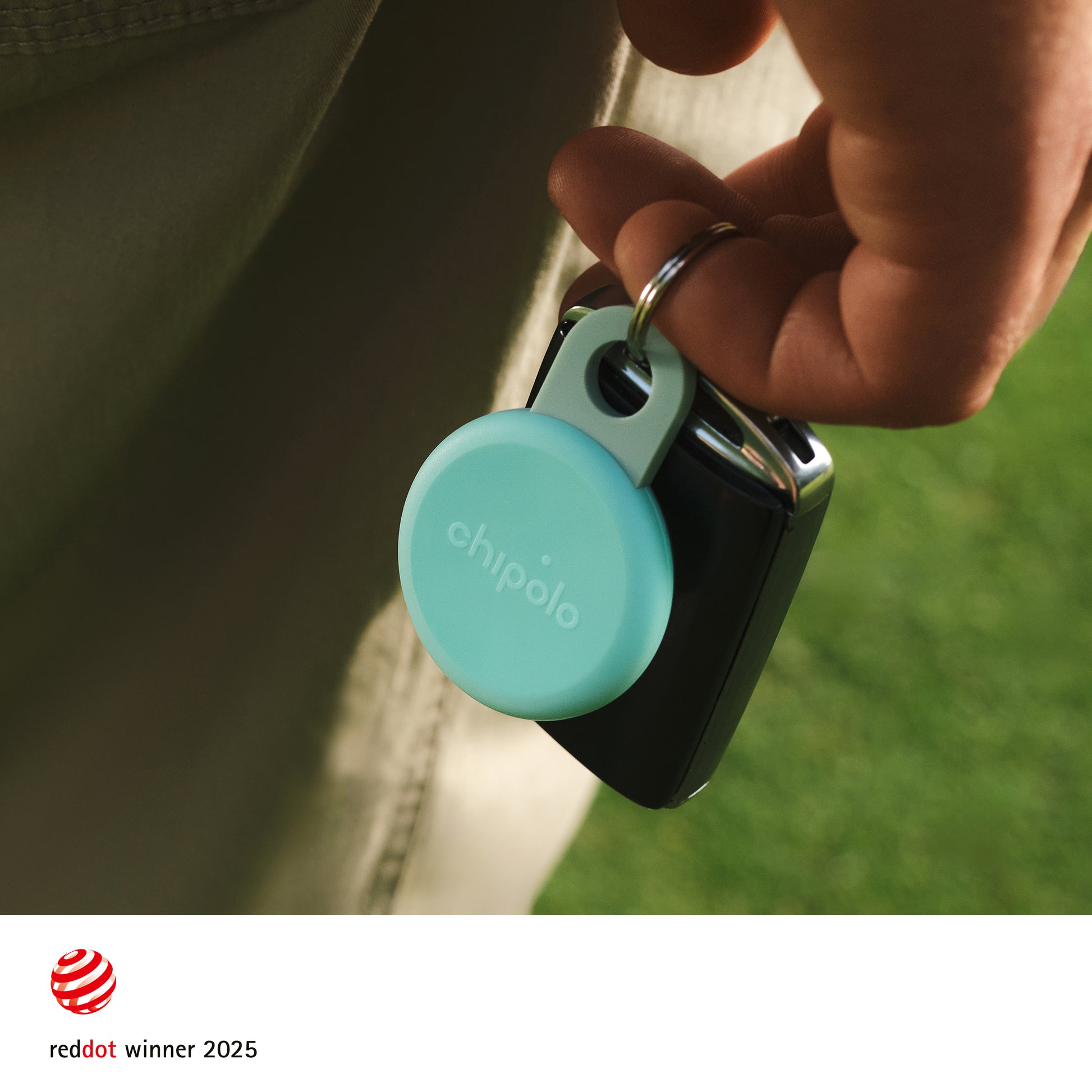 Person holding a keychain with a Chipolo tracker, featuring the Red Dot Award logo.