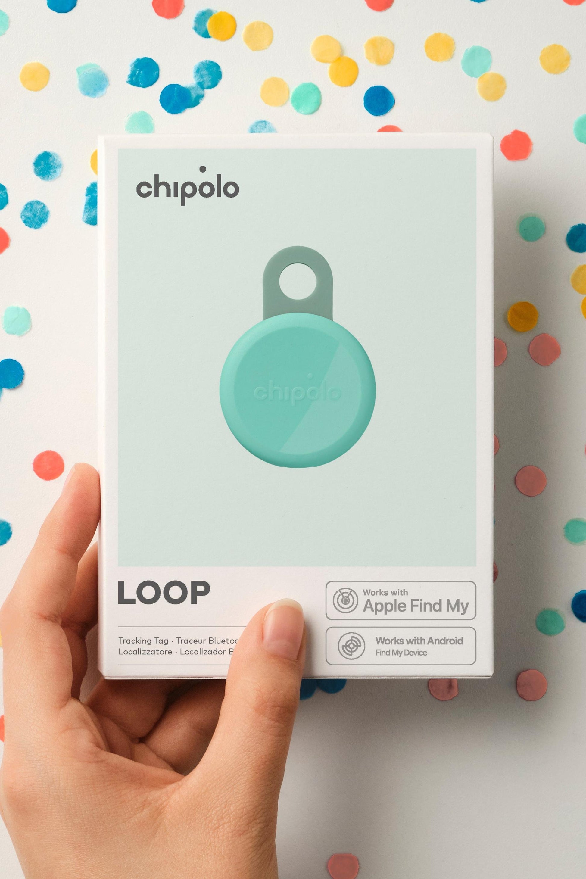 Hand holding a Chipolo Loop device packaging against a colorful polka dot background