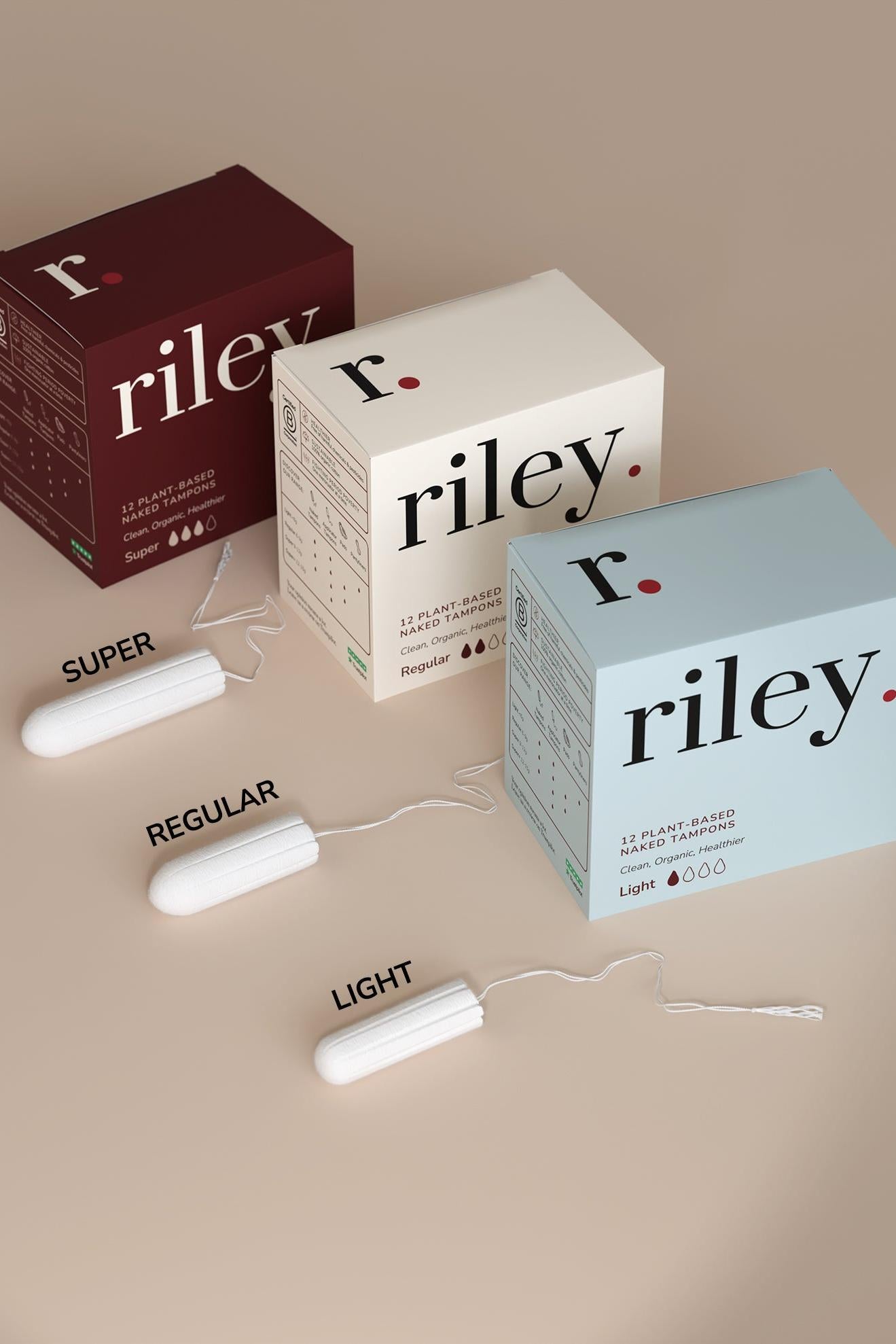 Three boxes of Riley tampons with tampons displayed in front on a beige background