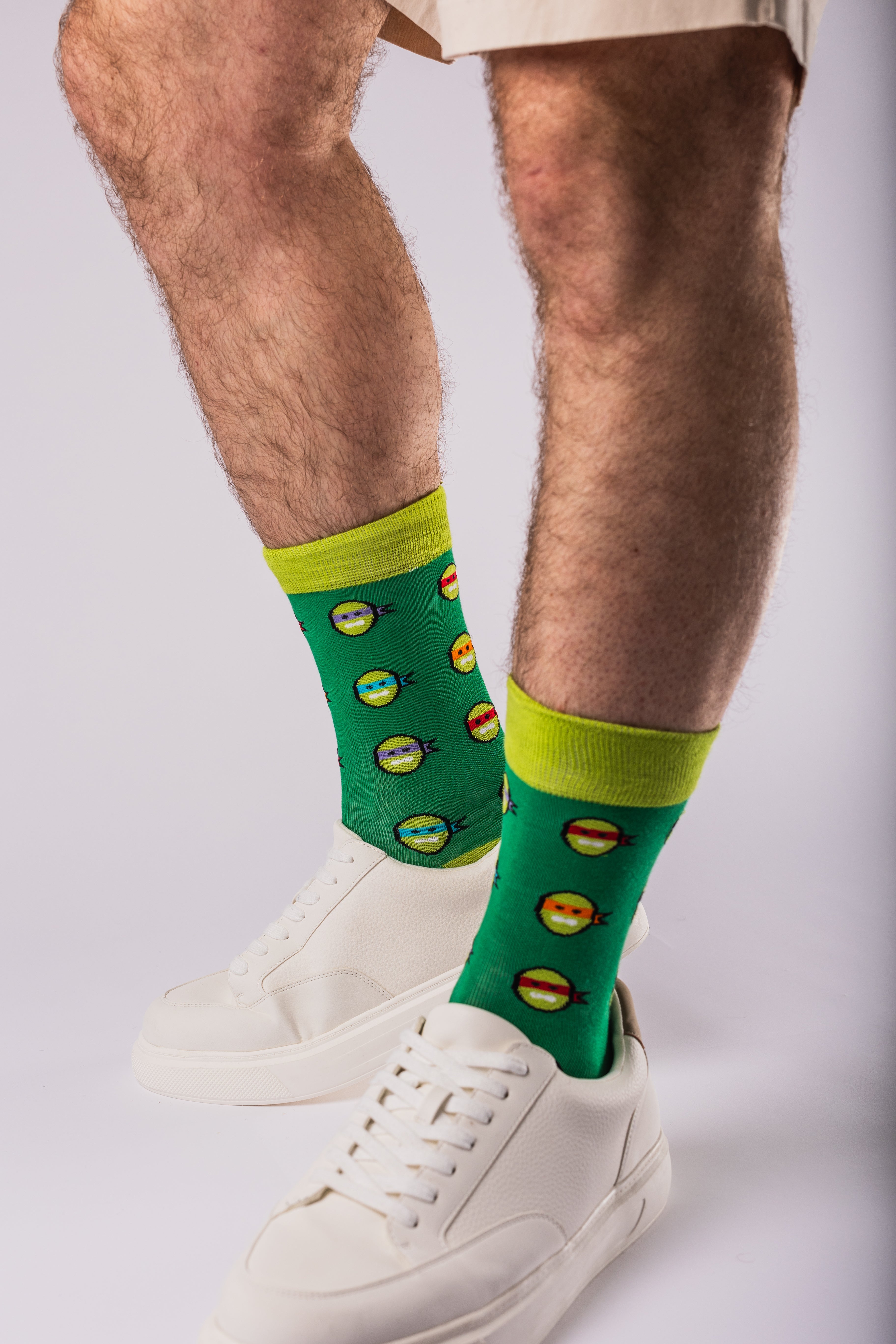 Man wearing green bamboo socks with turtle print and white trainers