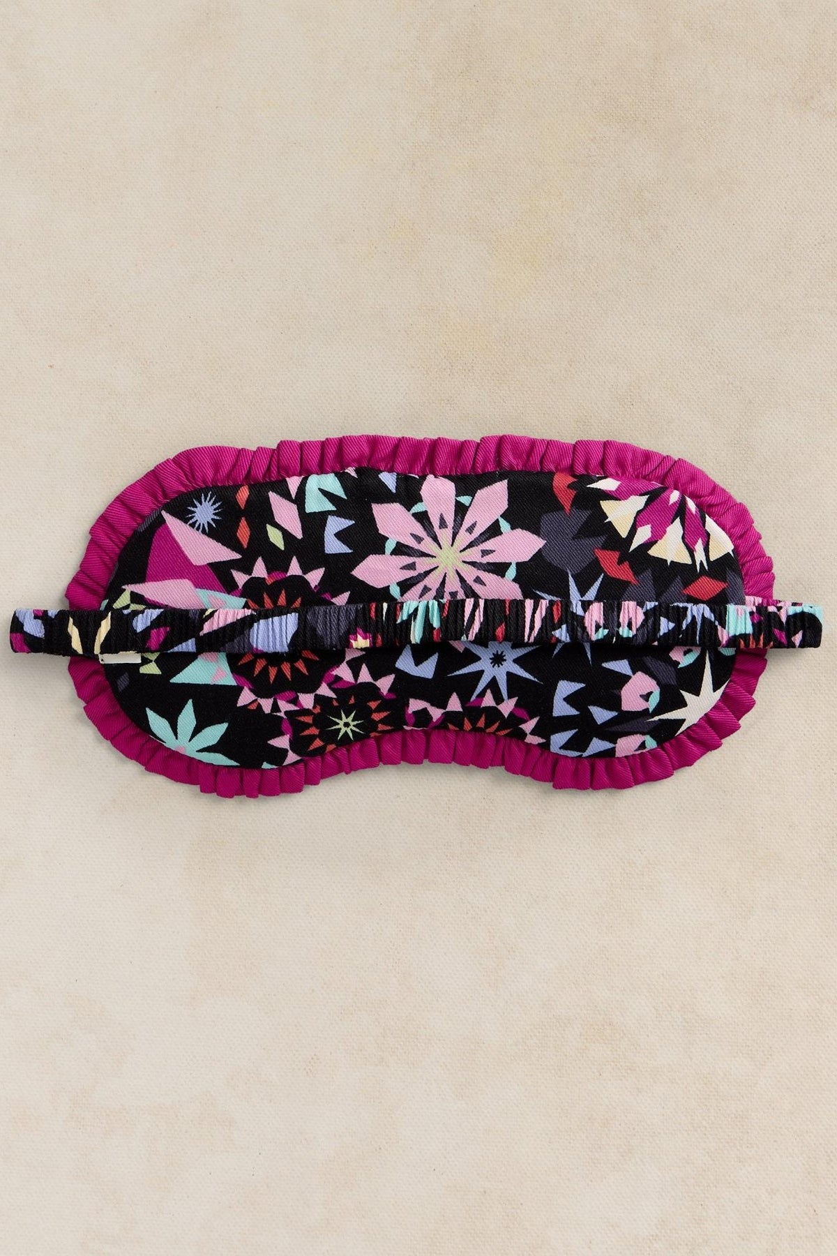 The back of a black print eye mask showing a soft elastic head band.