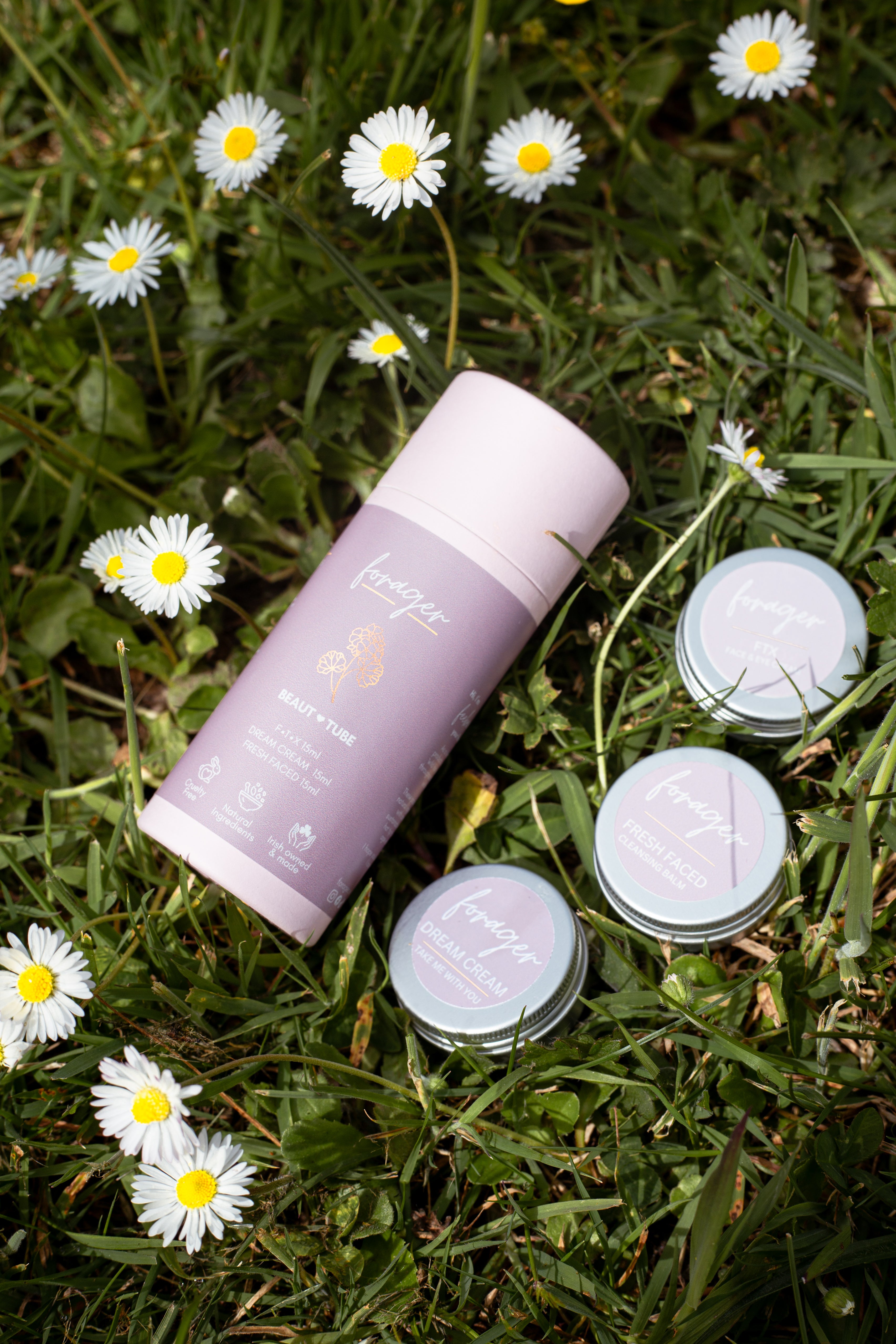 Cosmetic bottles with a purple label on grass with daisies