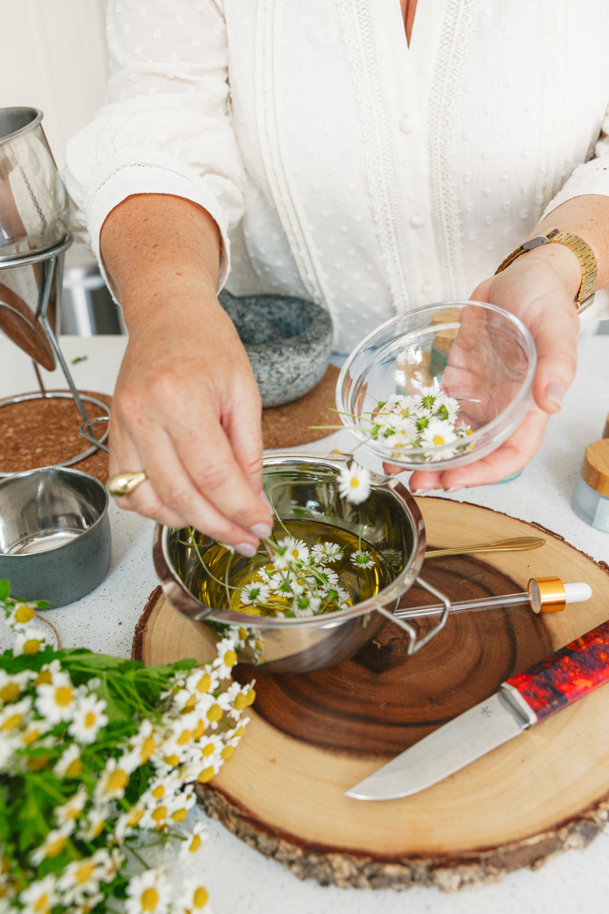 Person preparing a dish with daisies on a wooden board