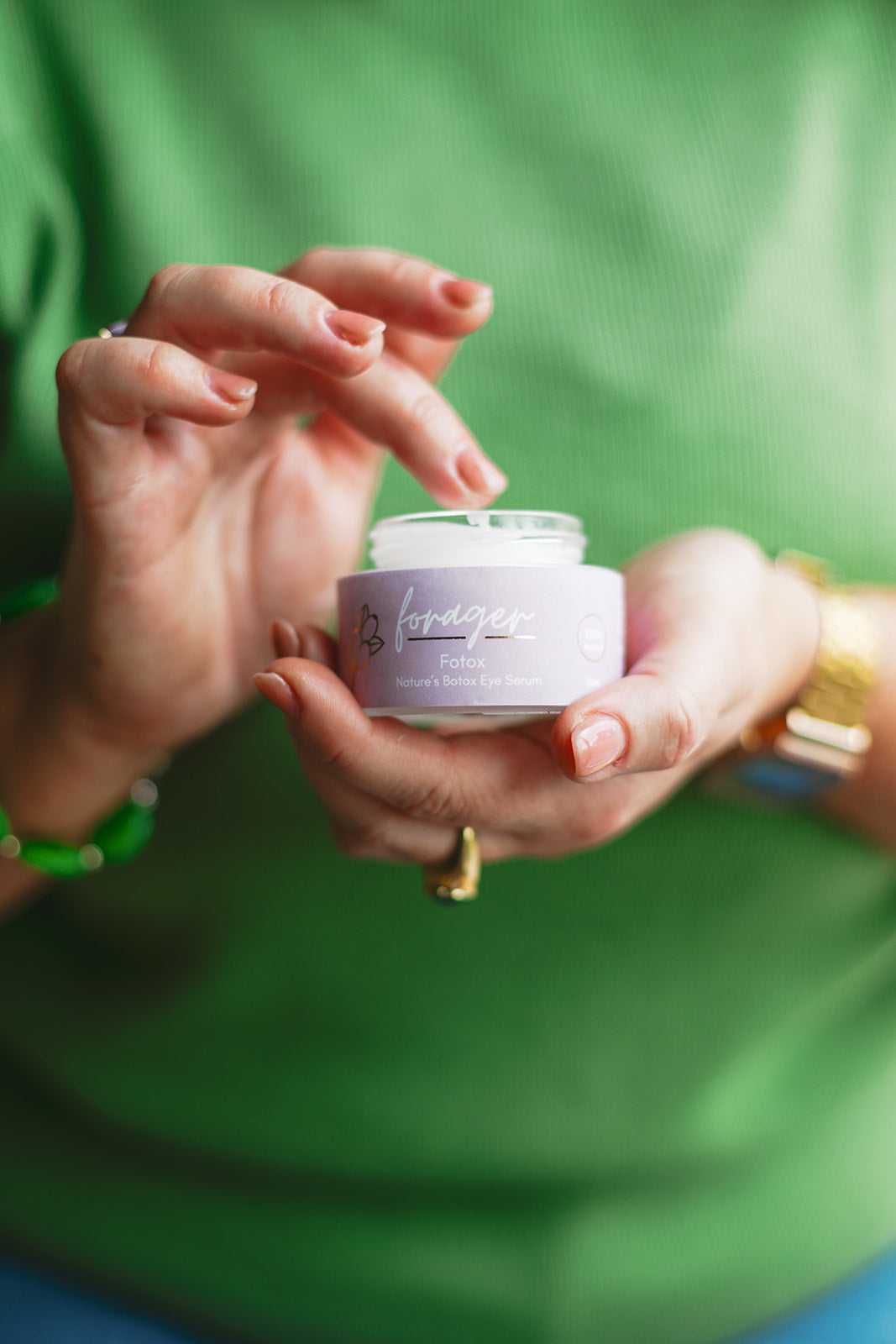 Person holding a small purple jar with a green background