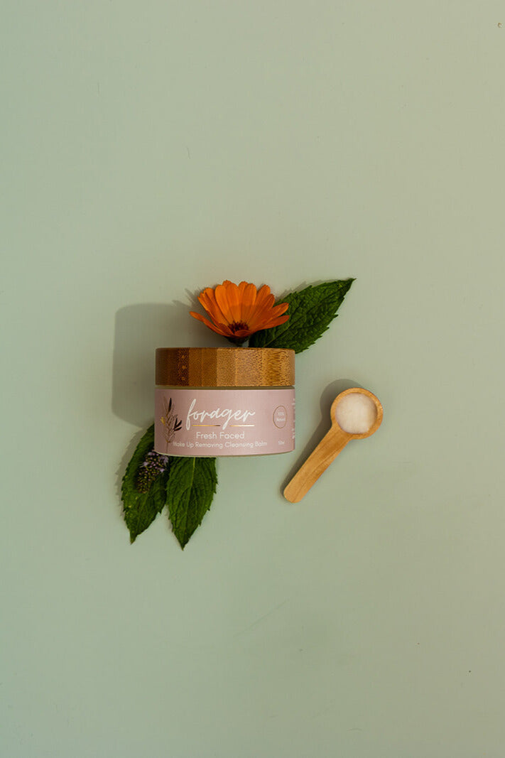 Jar of cream with a wooden spoon and flower on a light green background