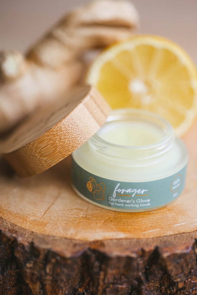Jar of 'Forager' hand cream on a wooden surface with a lemon slice in the background