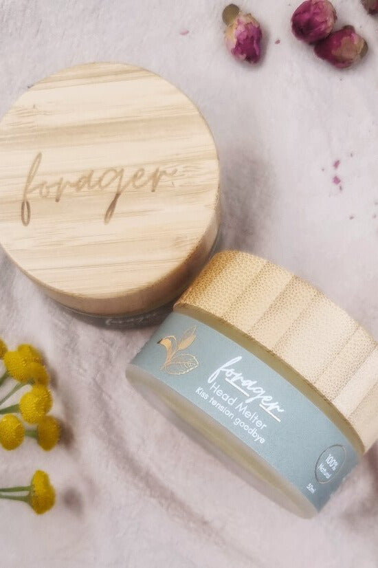 Jar with wooden lid and 'forager' branding on a light background with dried flowers.