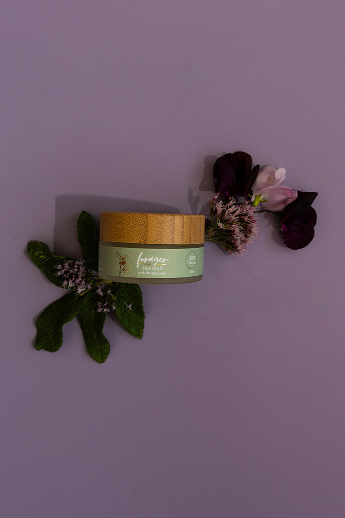 Green jar with wooden lid on a purple background with flowers