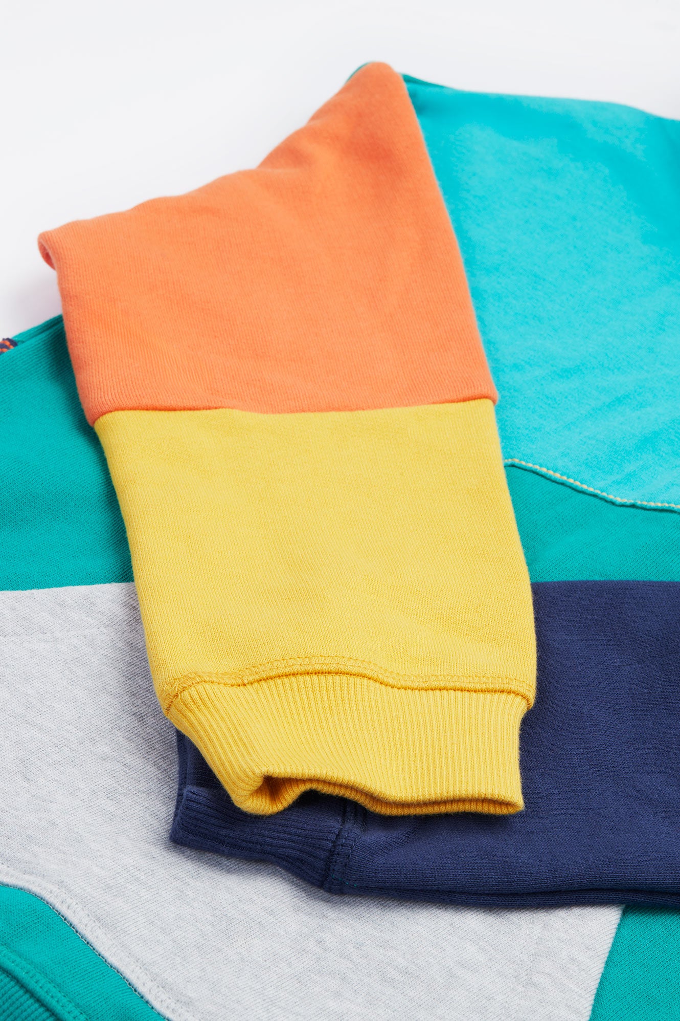 Close up of orange and yellow colour-block sleeve on frugi organic cotton hoodie.
