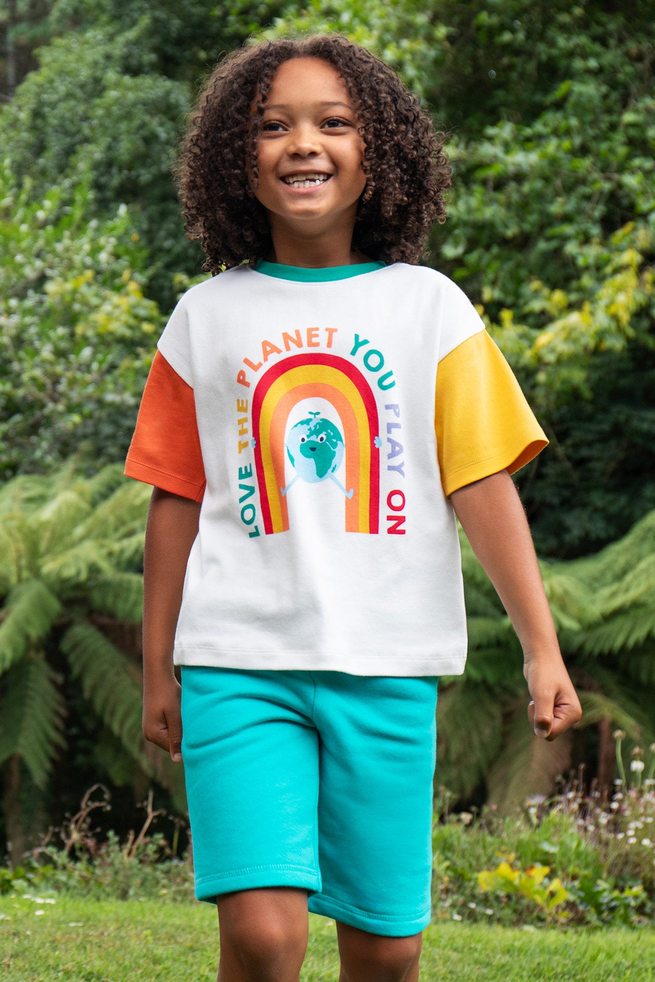 Child wearing the Frugi Samson Shorts in Seamoss, playing outdoors in a natural setting.
