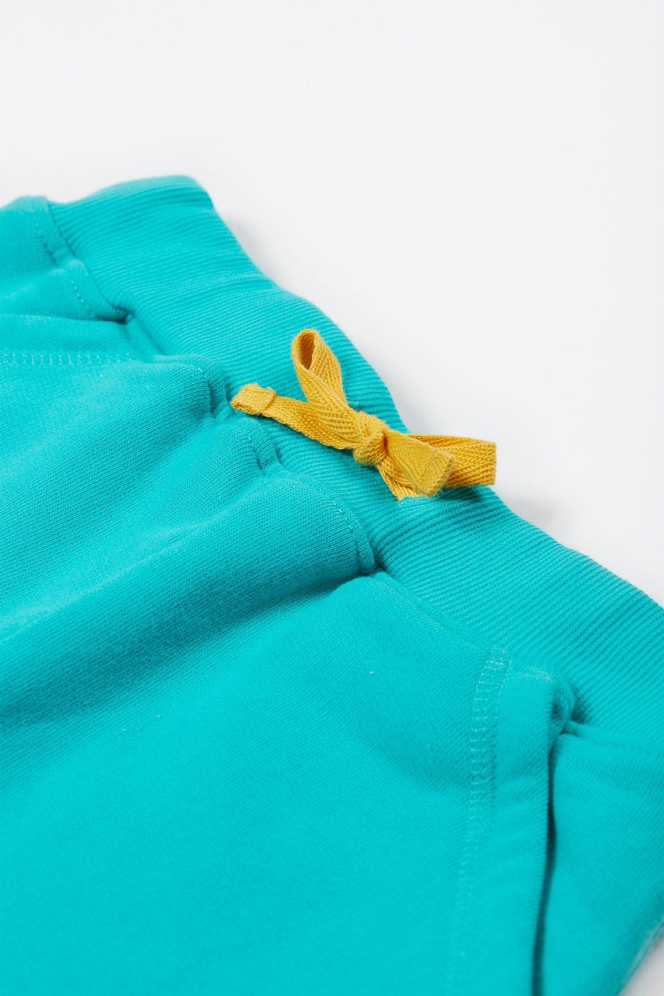 Detailed view of the elasticated waistband with a yellow drawcord on the Frugi Samson Shorts in Seamoss.