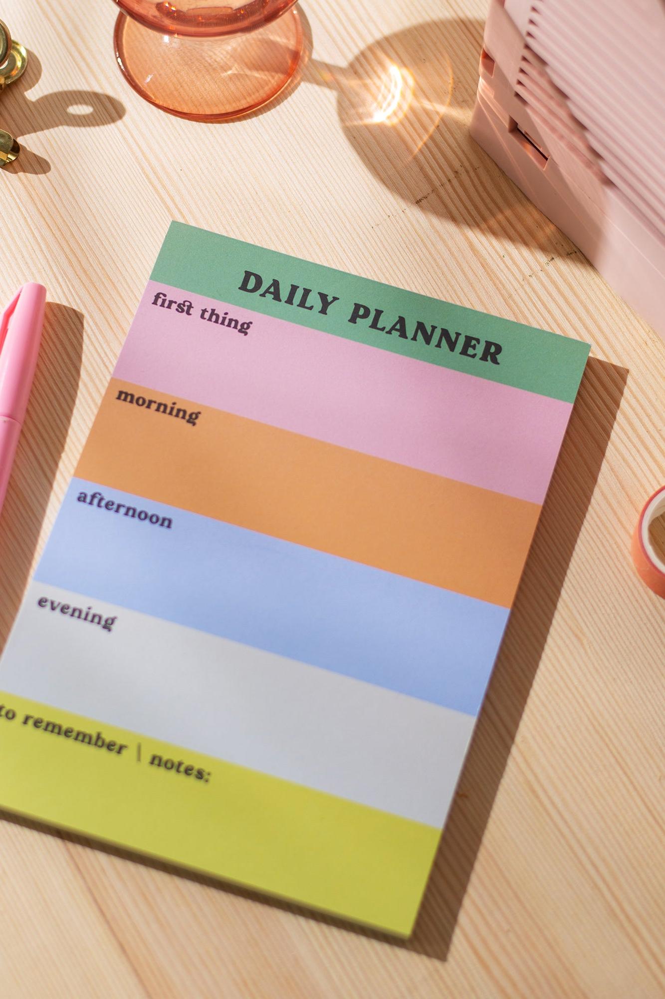 Colourful daily planner on a wooden surface with stationery items.