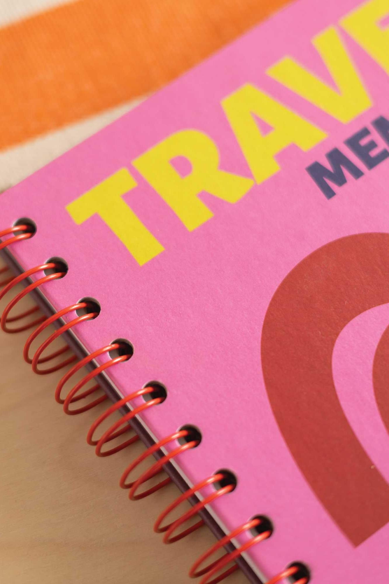 Pink travel notebook with yellow text on a wooden surface