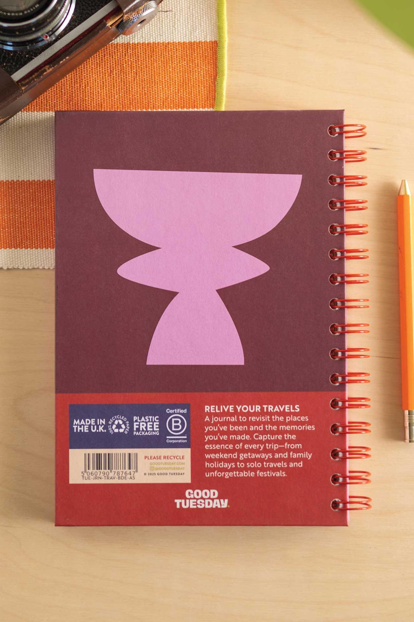 Notebook with purple design on a wooden surface with a pen and camera.