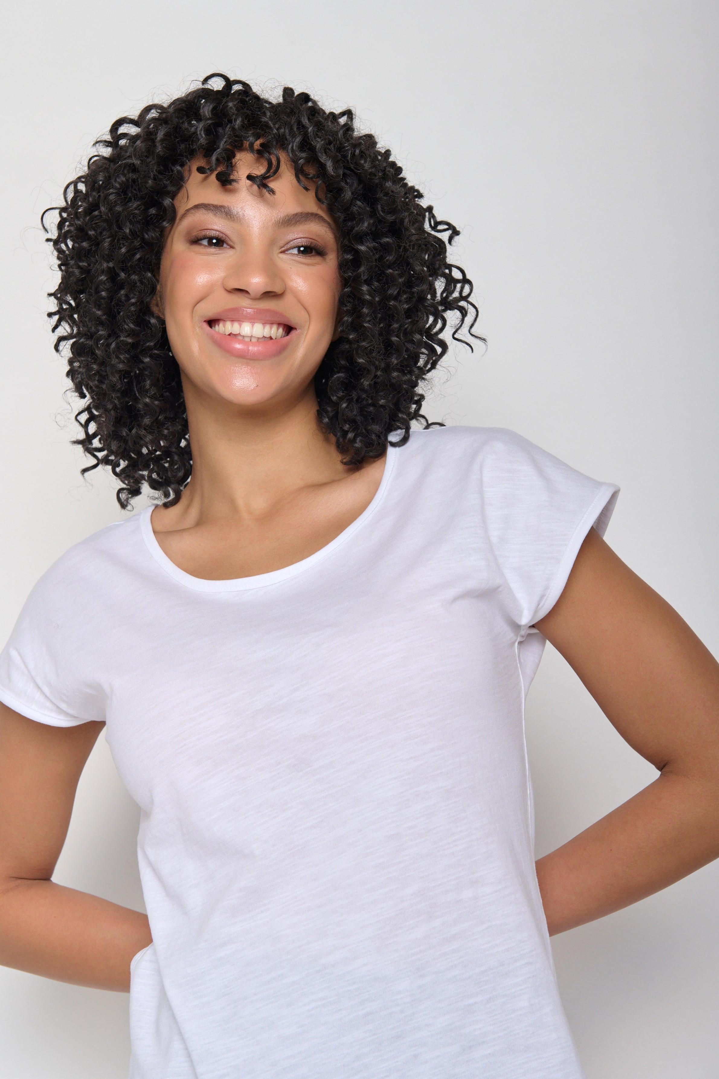 Model wearing the white Greenbomb Basic Cool Tee in a casual pose with arms slightly lifted, showing the soft organic cotton drape.