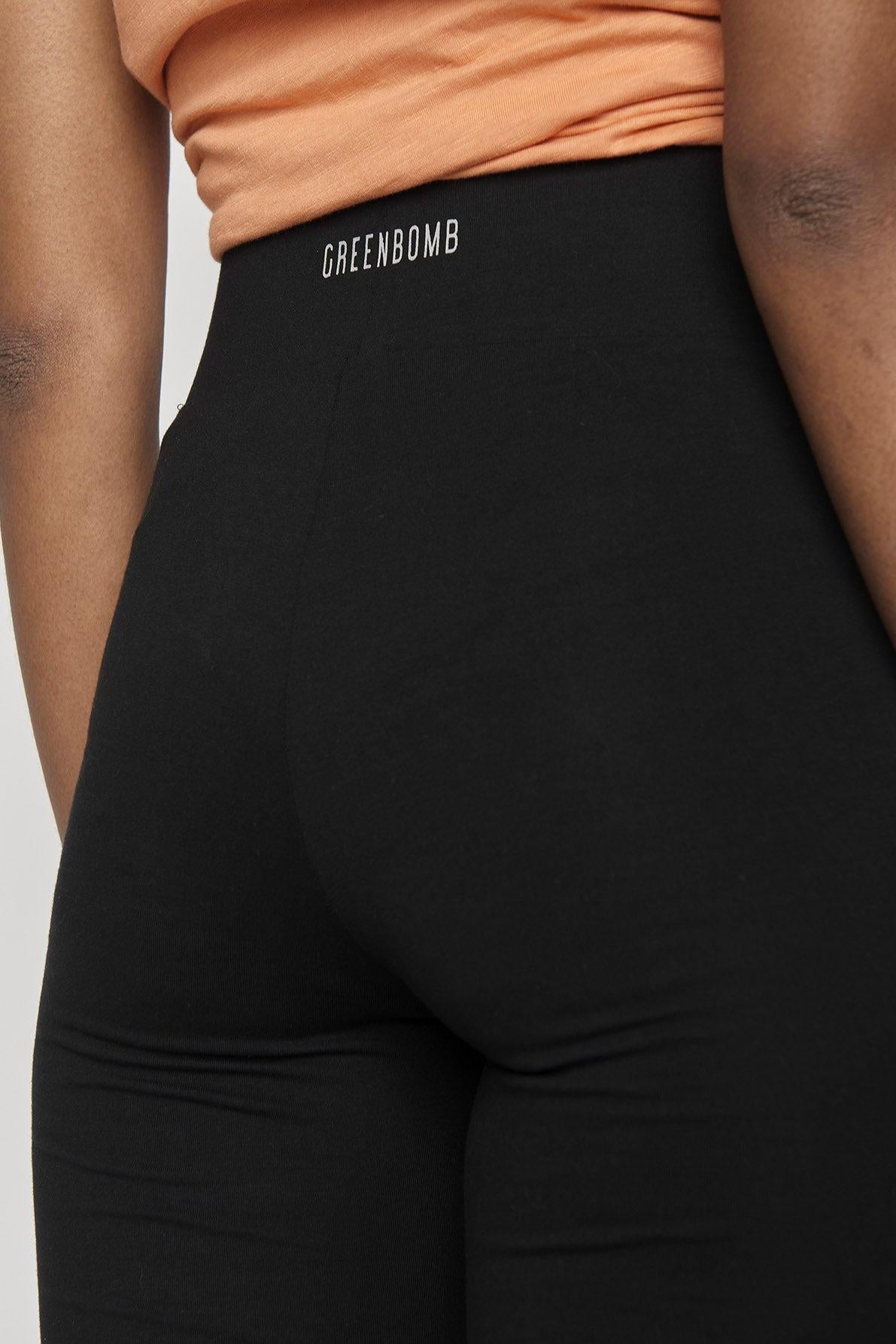 Back view of black bicycle shorts with greenbomb writing on the back
