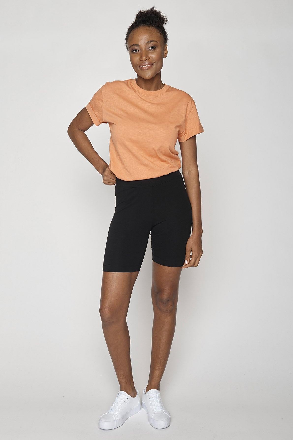 Model wearing black bicycle shorts with apricot coloured t-shirt