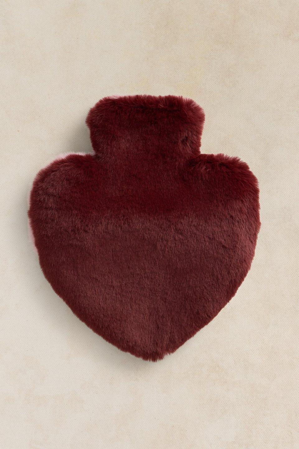 A fluffy red hot water bottle in a heart shape for a Christmas gift.