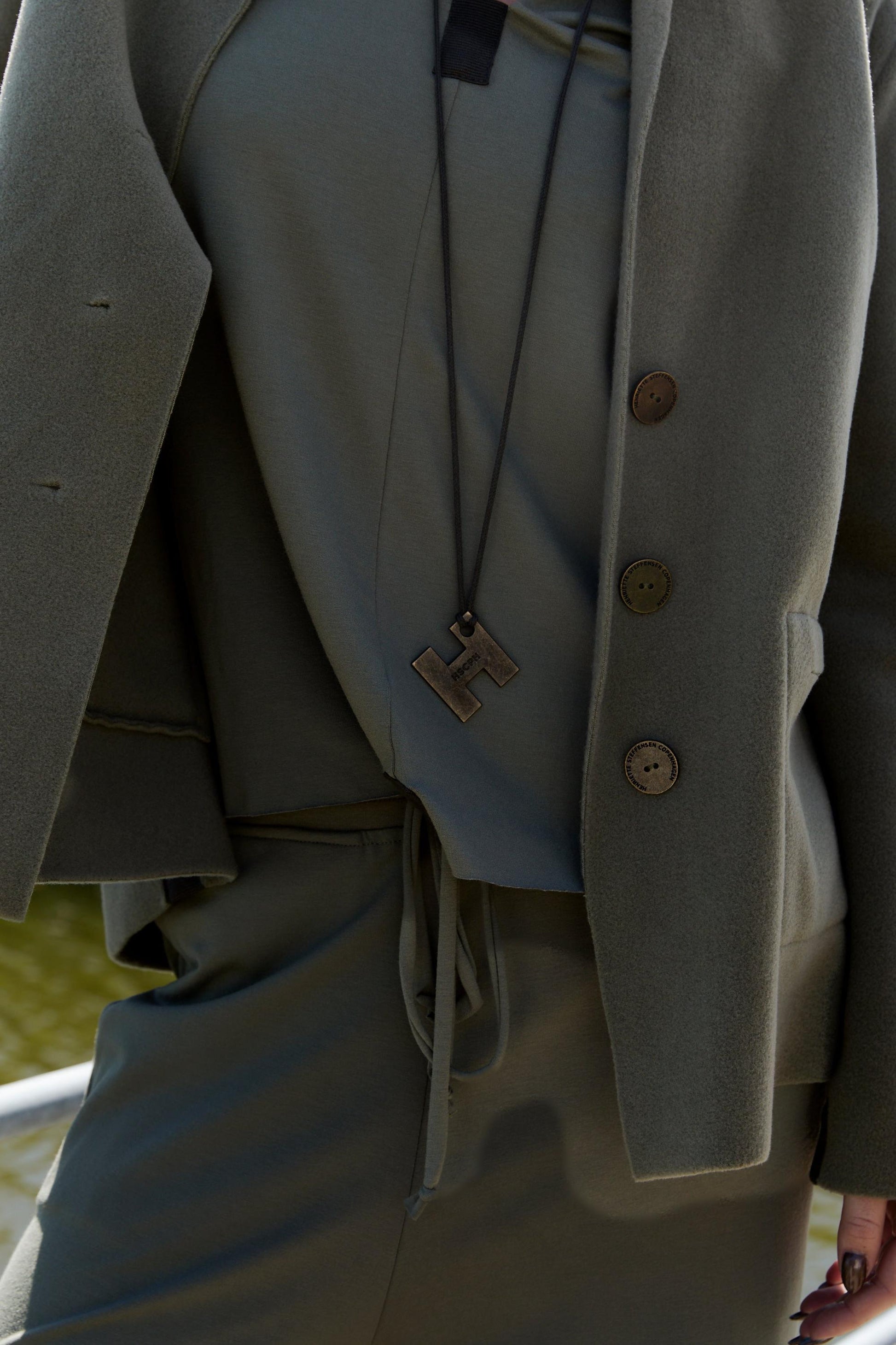 Close-up of a person wearing a Henriette Steffensen outfit with a necklace.