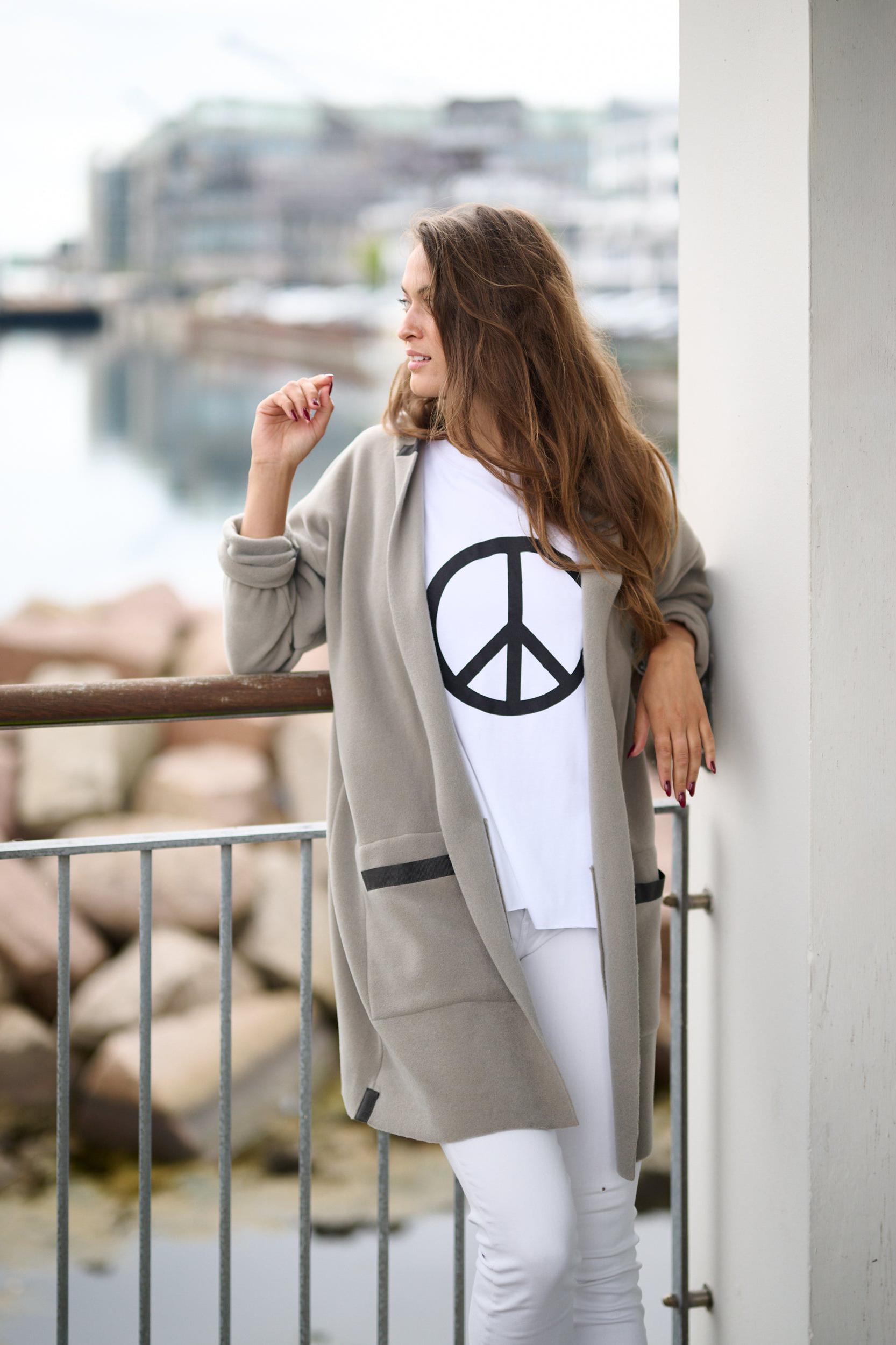 A woman wearing the hooded cardigan outdoors, standing by a railing with a relaxed stance.